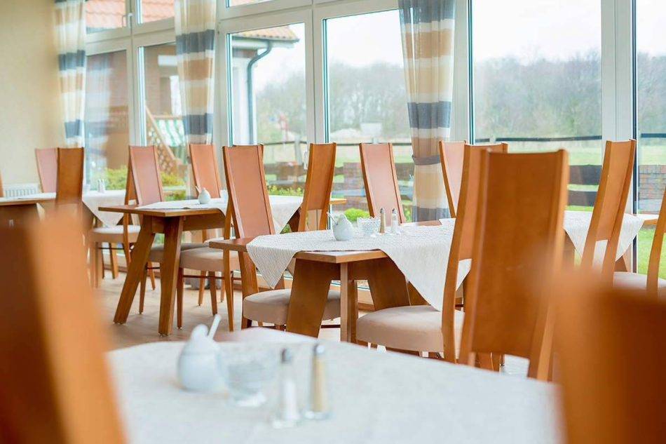 Elegante Sitzgruppen Im Wintergarten Des Nige Hus Laden Zum Verweilen Ein, Während Das Atemberaubende Panorama Im Hintergrund Für Eine Besondere Atmosphäre Sorgt.