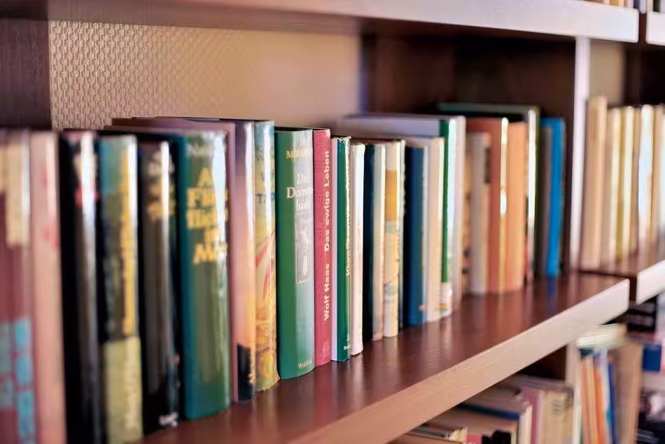 An Inviting Bookshelf Filled With A Colorful Mix Of Novels, Mystery Novels, And Nonfiction Is Waiting To Be Discovered By Curious Readers.