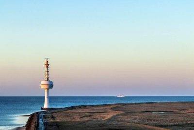 Der Radarturm Auf Neuwerk Mit Blick Auf Die Elbe. Im Hintergrund Fährt Die Helgoland-Fähre.