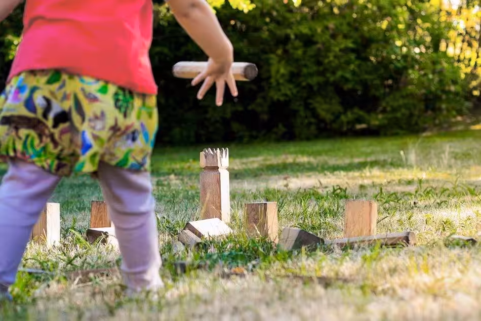 Ein Junges Mädchen Konzentriert Sich, Während Sie Einen Kubb-Wurfstock In Der Hand Hält Und Auf Das Gegnerische Team Zielt.